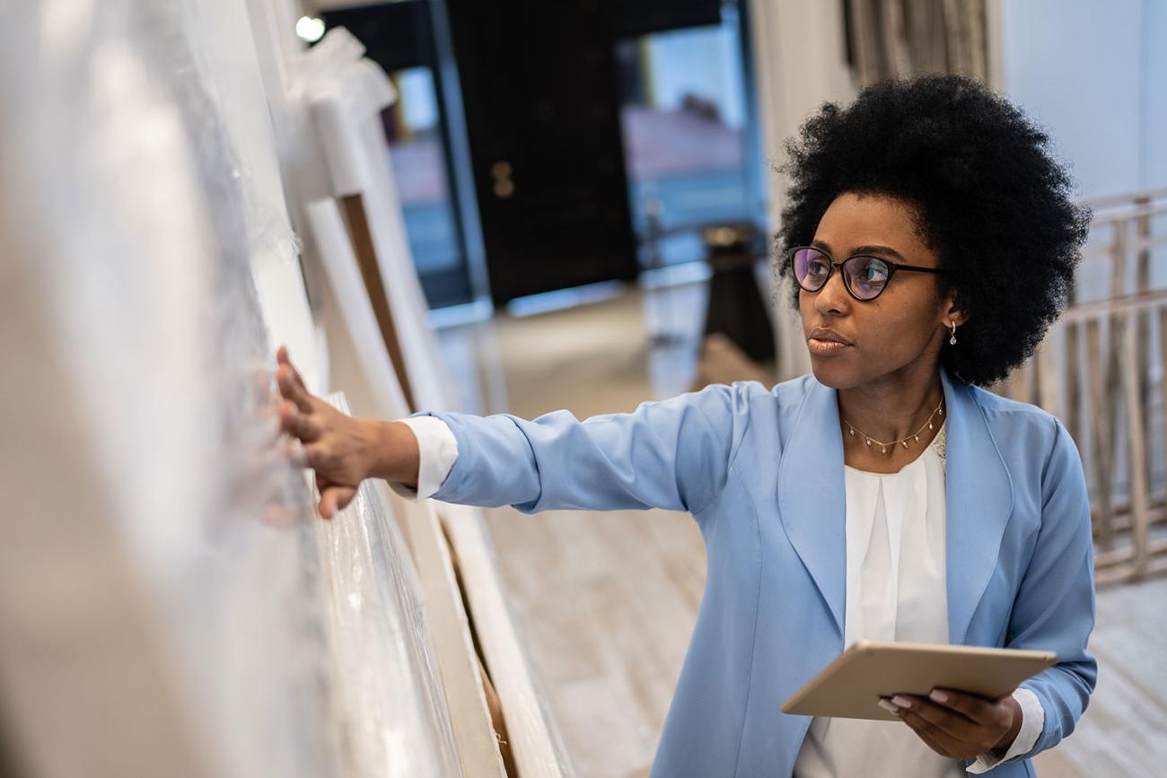 African American woman in light blue blazer standing at chalkboard with book in her hand