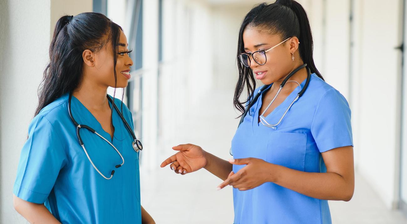 Two young nurses chatting in hospital hallway