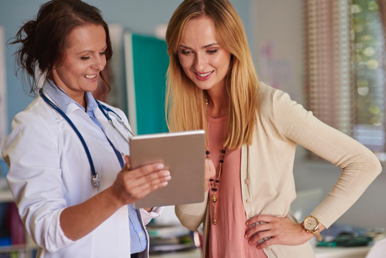 Woman showing a patient an iPad. Image by Freepik.