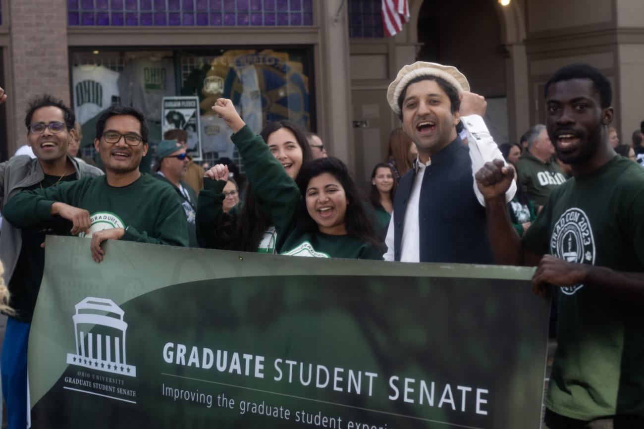 A group of graduate students behind a Graduate Student Senate banner