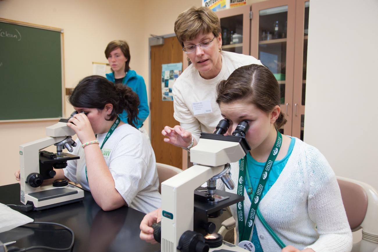 Tech Savvy participants look into microscopes in a lab