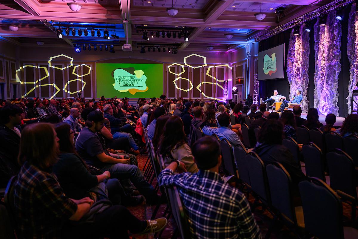 Room full of people watching panelists on stage