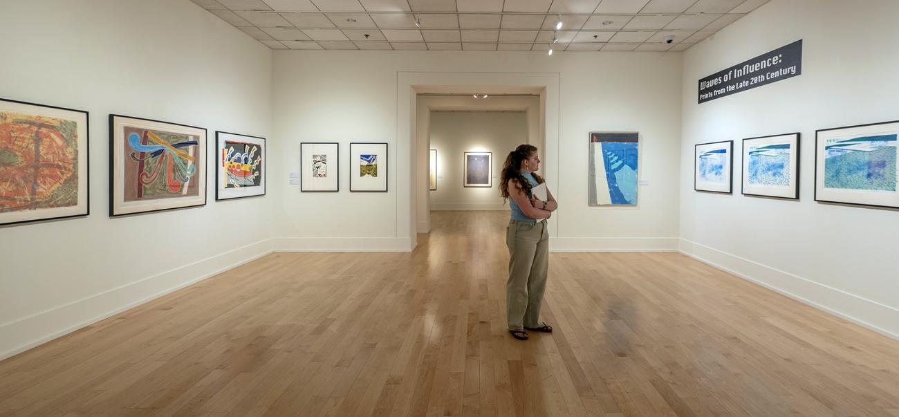 Person standing in gallery surrounded by artwork