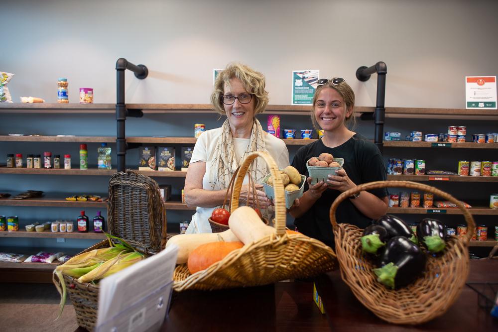 Two people standing in Cats Cupboard with baskets of fresh produce.