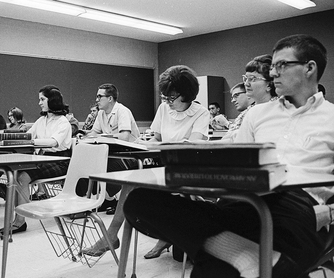 Students sit at desks in a classroom.