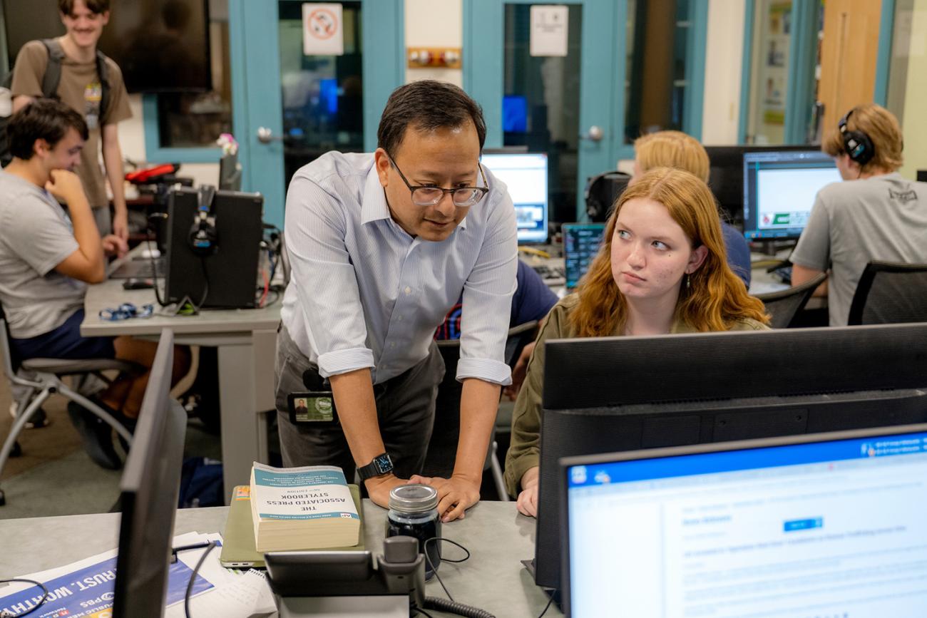 WOUB editor-in-chief helping student working a computer