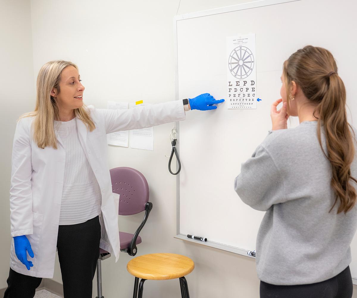 An instructor teaches in front of a classroom with a student volunteer.