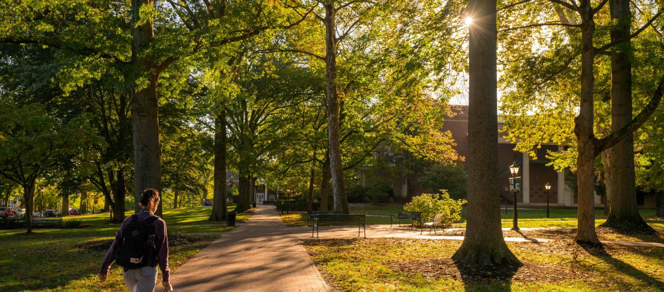 A student walks through the College Green during fall