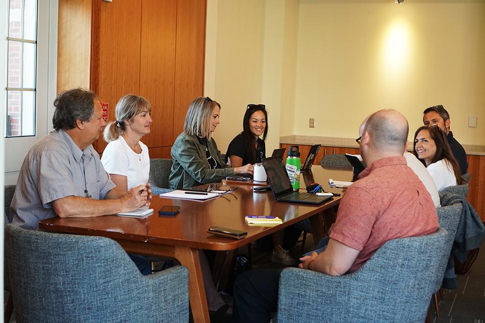 A group of 8 adults sitting around a table for a meeting