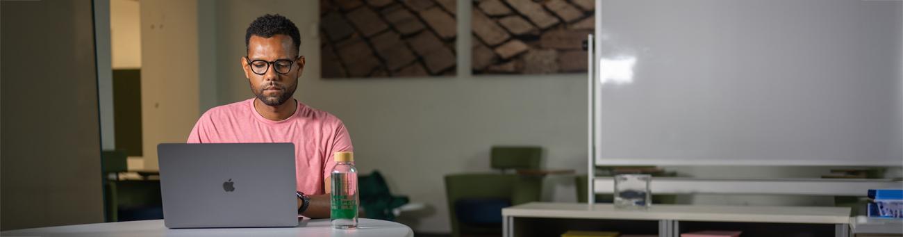 A person sits at a desk looking at a laptop.