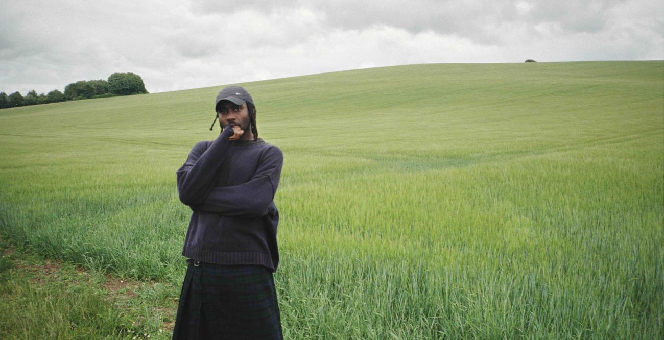 Dev Hynes standing in a grassy field