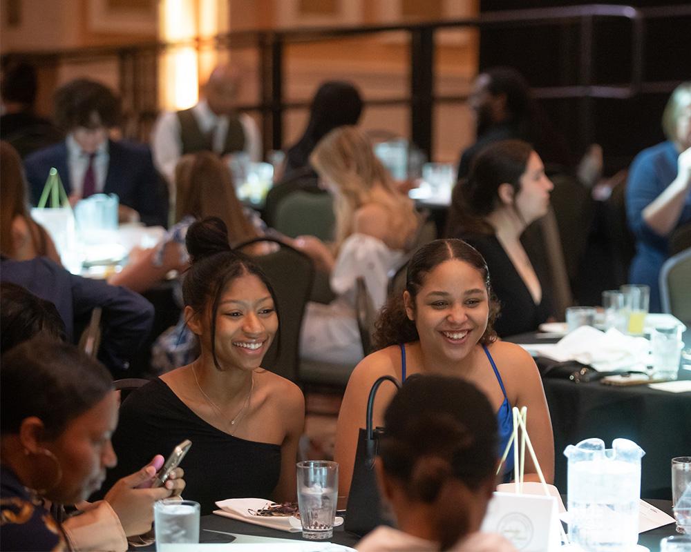 Students laugh and talk while enjoying a dinner at a leadership banquet.