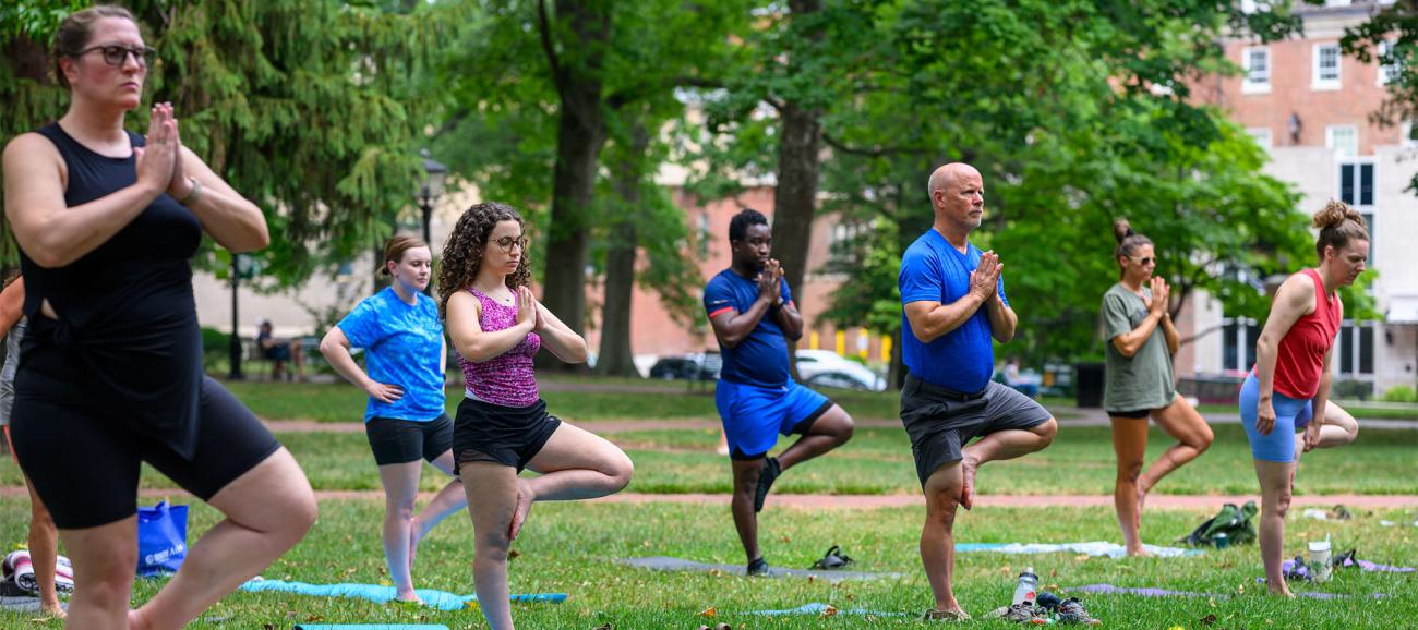 Students, faculty and staff do yoga on College Green.