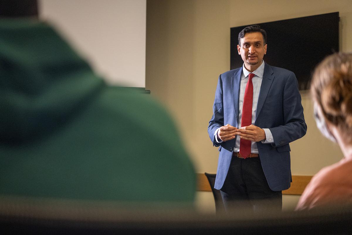 man in suit and tie speaking to a group of students