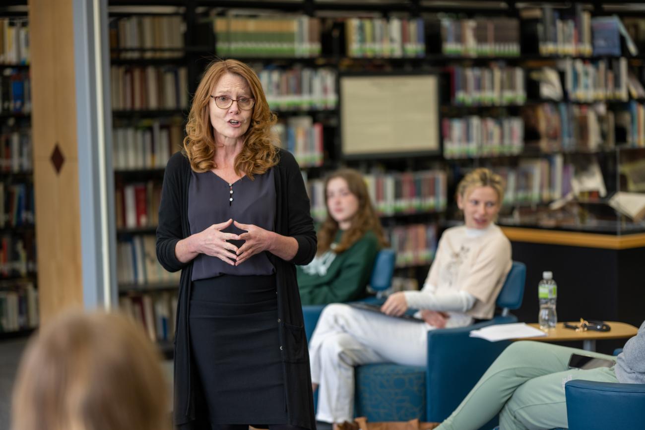 woman talking and standing in front of group of students