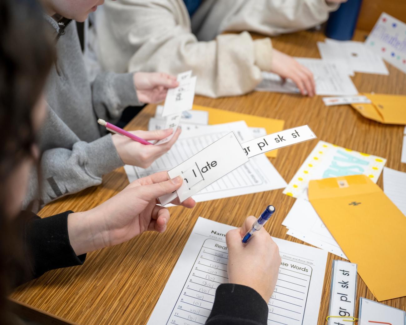 students holding flash cards with word prefixes for reading instruction