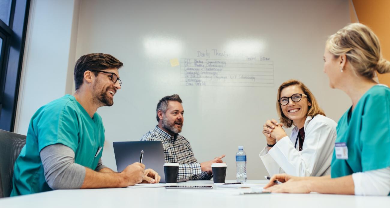 Nurses and doctors in an office space smiling and talking