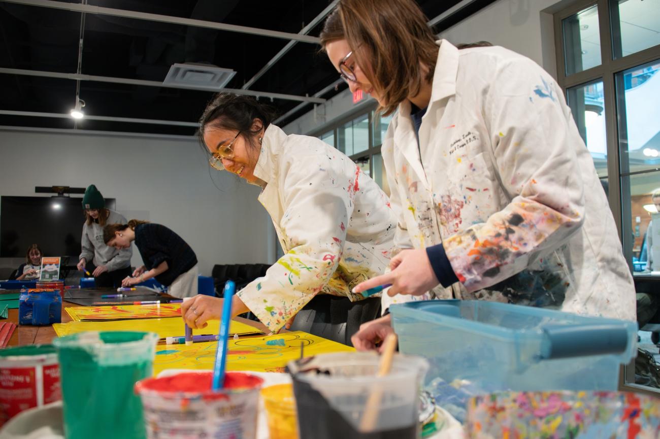 two people painting art with paint all over their painting clothes