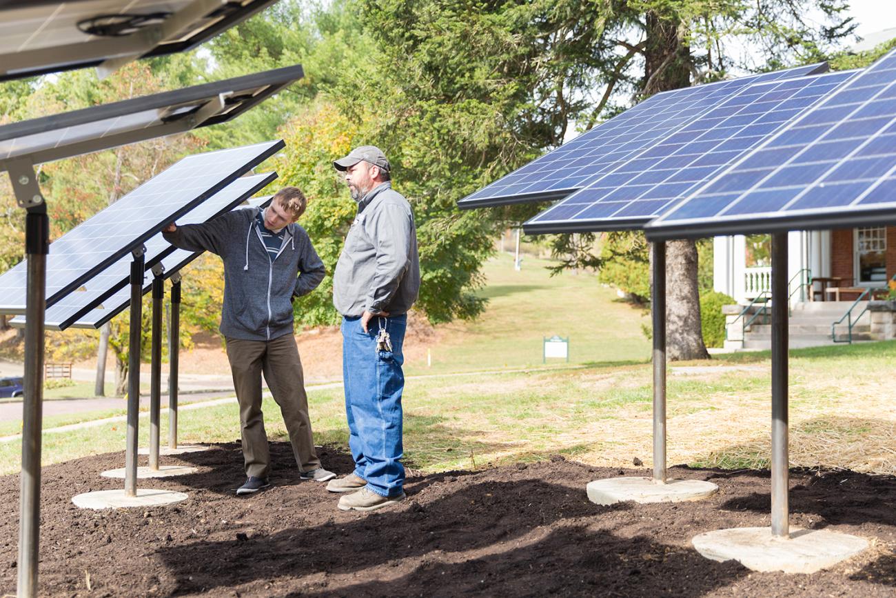 two men looking at newly installed solar panels in a yard or field