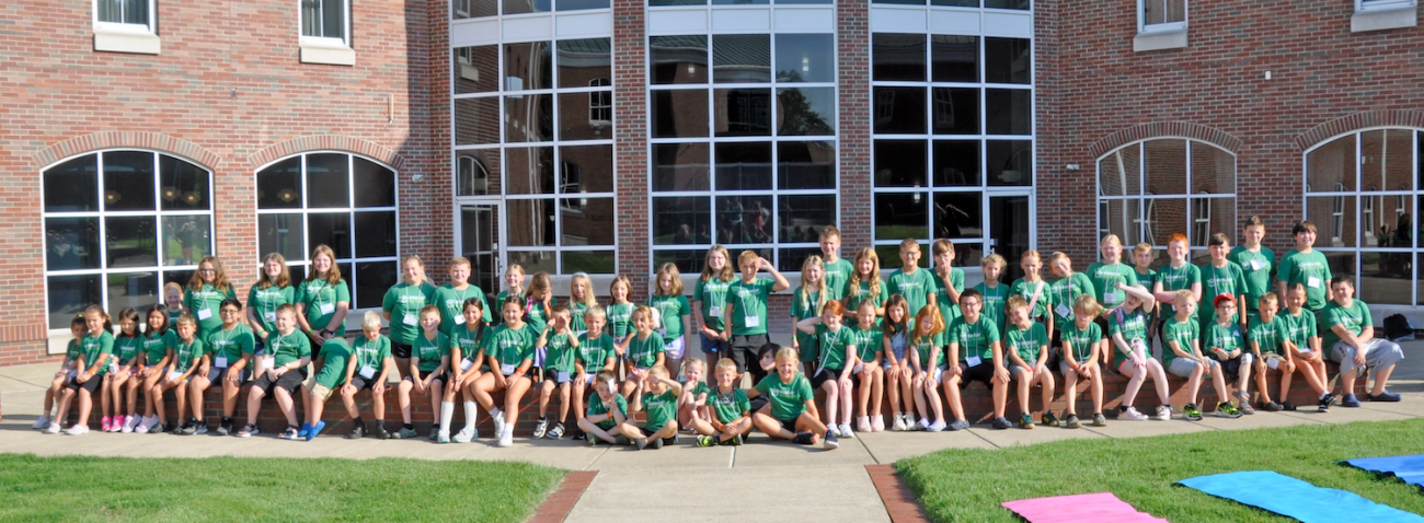 group of students in green tshirts posing for outdoor photo