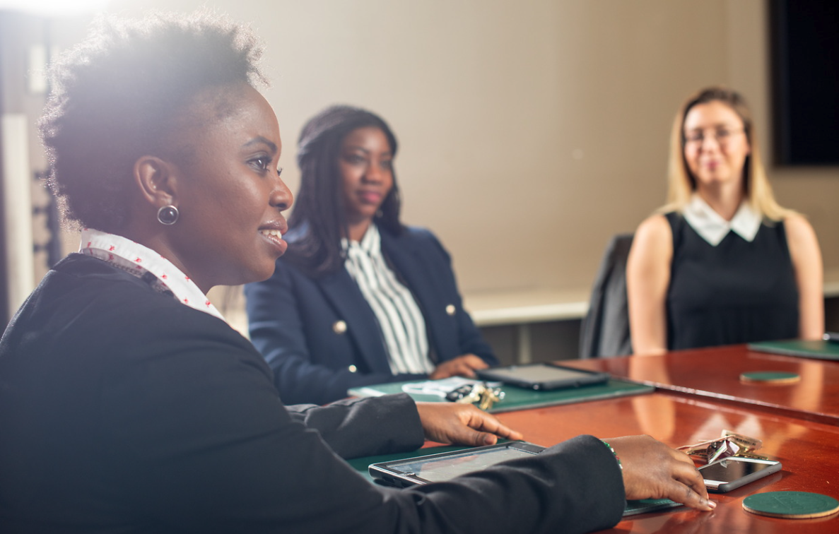 three women wearing business attire sitting at a conference table