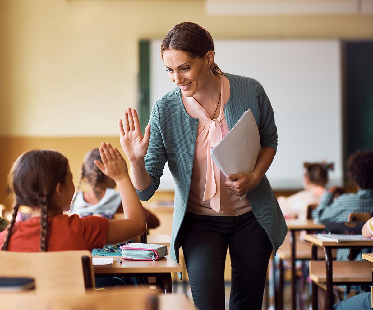 A stock image of a teacher giving a student a high-five.