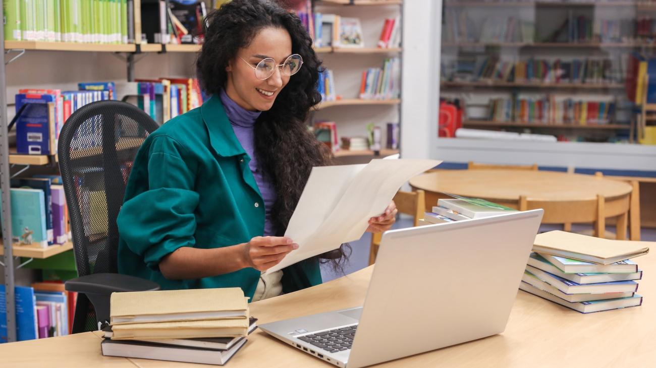 woman with a laptop on a desk in a library