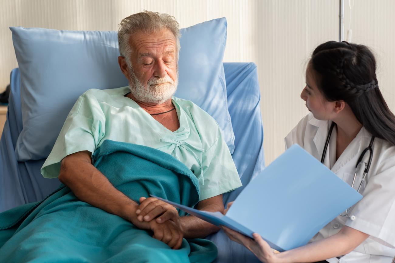 woman nurse with elderly man in a hospital bed