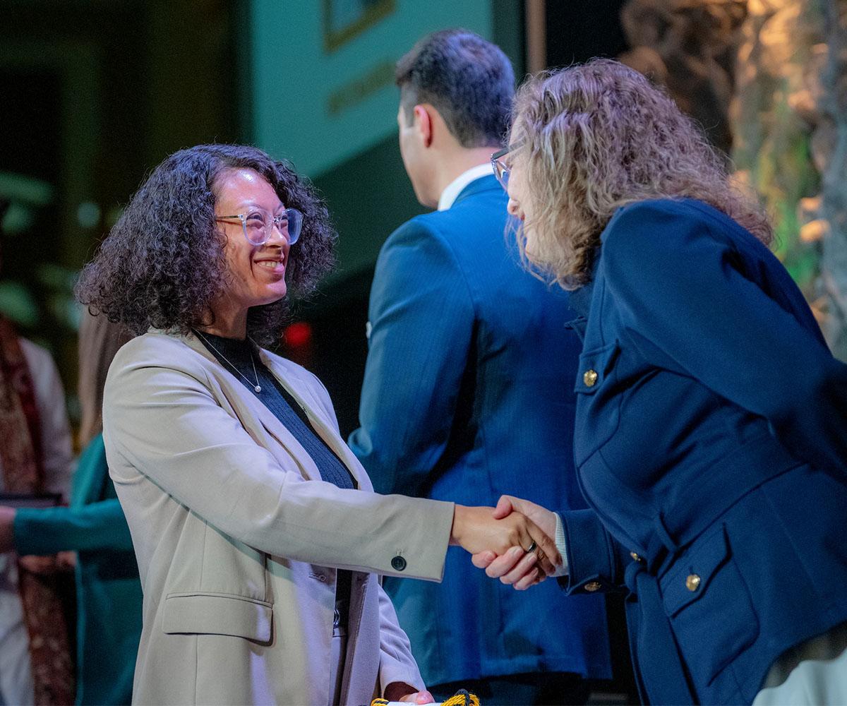 A university administrator presents an award to a student.