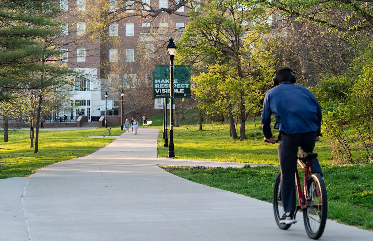 Student riding their bike on the OHIO campus through the shadows of the morning sun. 