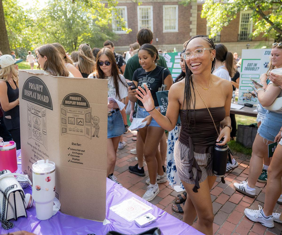 A student waves as the leave a student organization sign up table at the Student Involvement Fair.