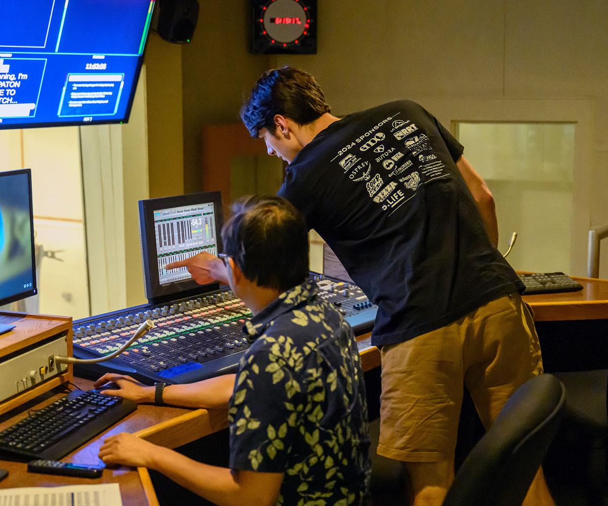 A student works on sound equipment during a broadcast.