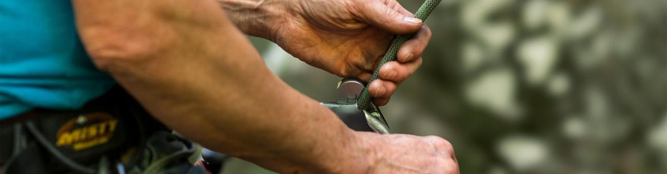 man fastens ropes as he prepares to do some rock climbing