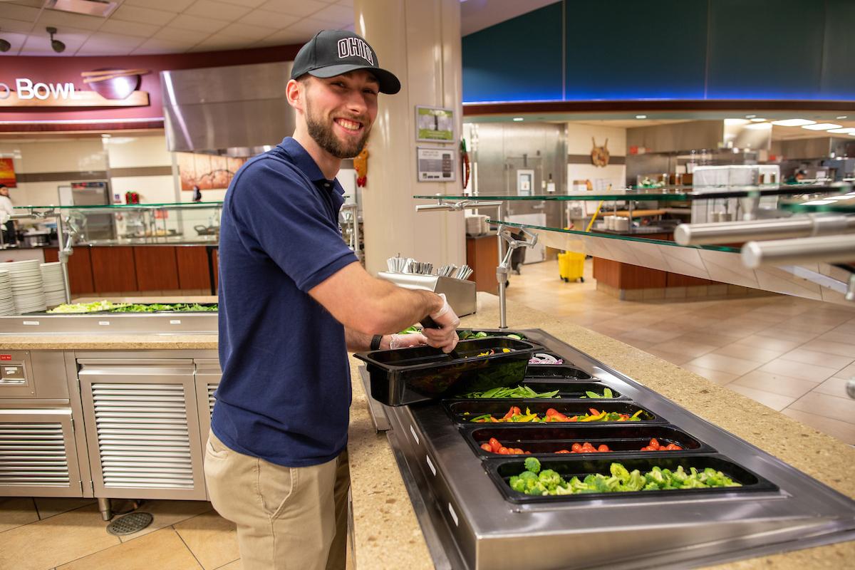 student employee at Nelson Dining Hall refilling the salad station
