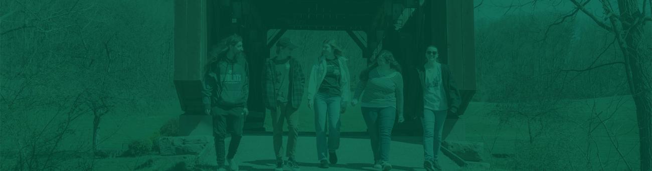 Four students talk and walk together across a bridge on the OHIO Lancaster Campus.