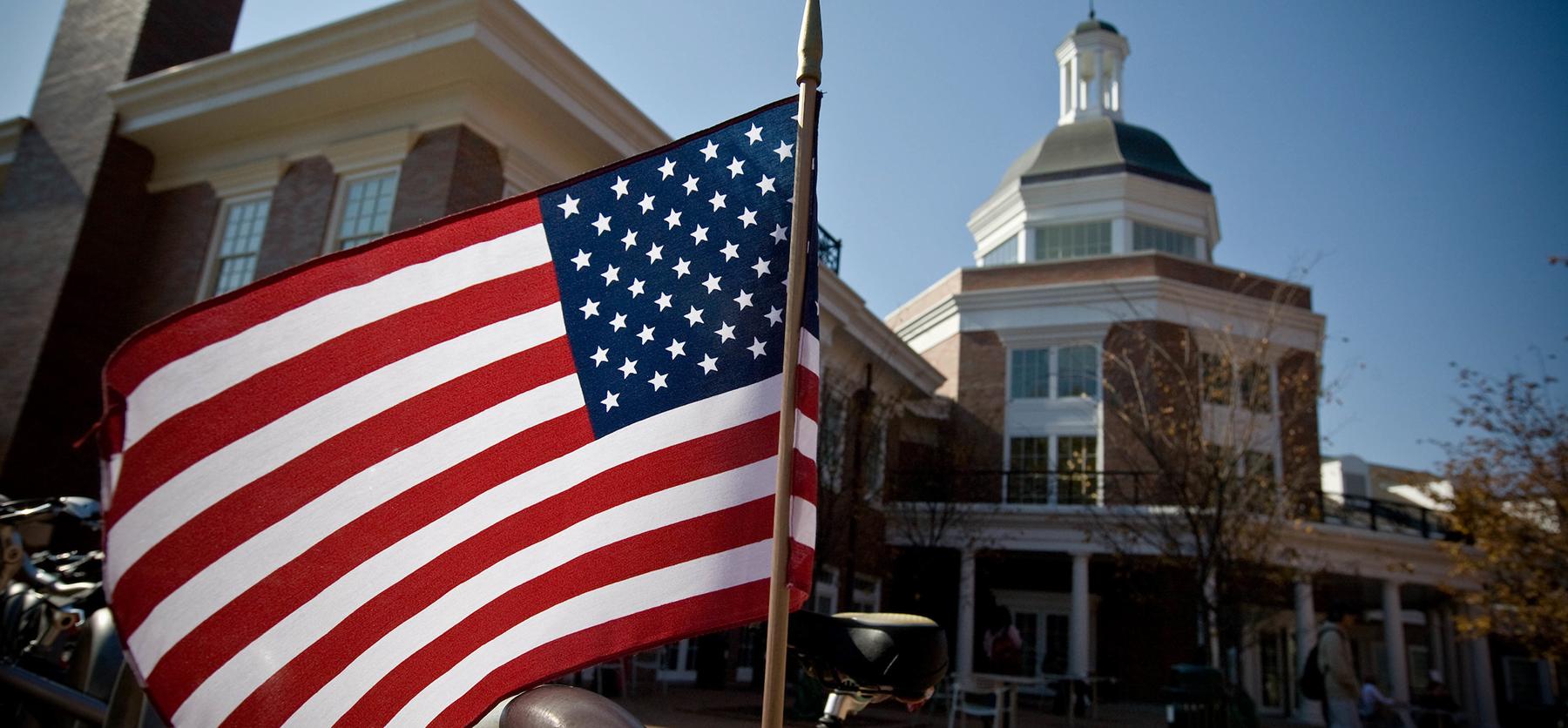 An American flag waves in the wind in front of the Ohio University Baker Center.