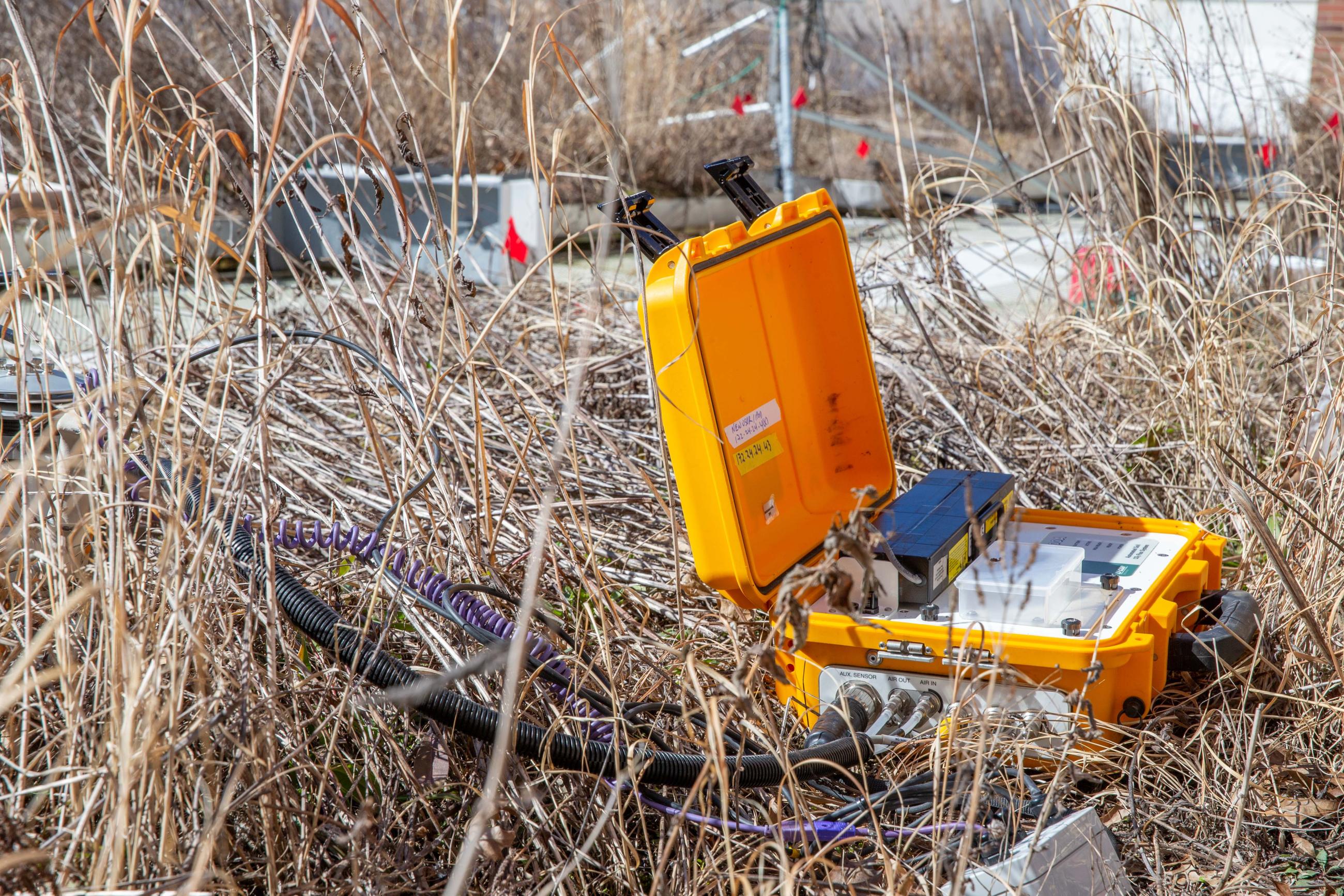 A yellow hard case sits in one of the Schoonover green roof beds with instruments inside and hoses and cables connected to sensors in the soil.
