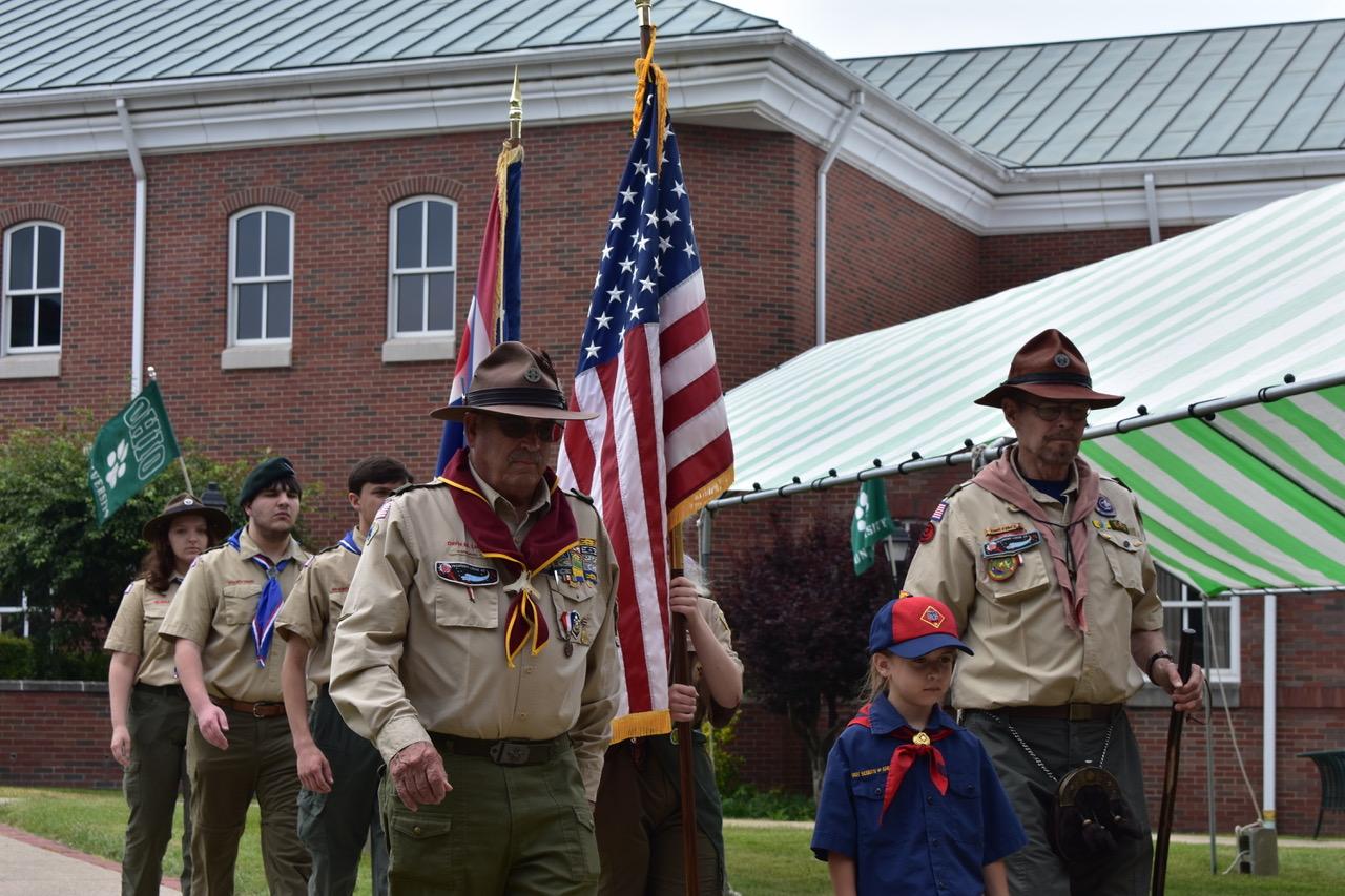 two adults and six children in Scout uniforms carrying Ohio and USA flags