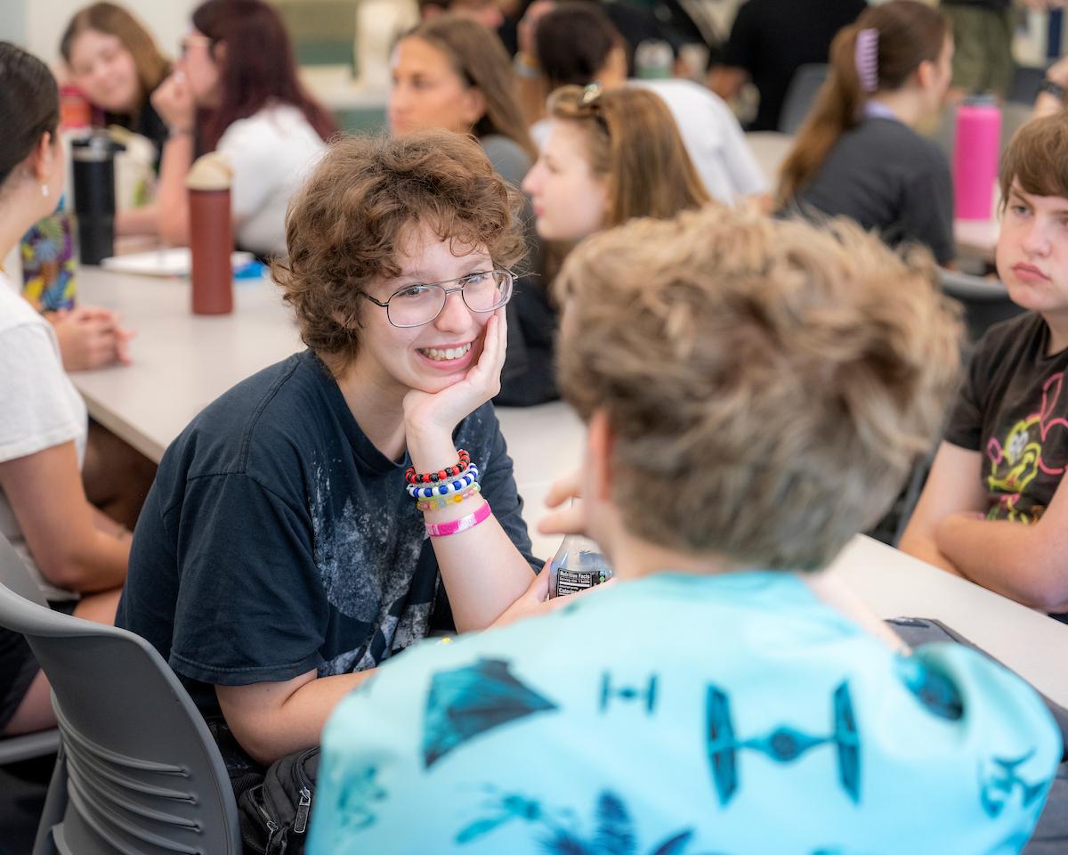 One student is smiling and speaking to another at the Early Experience Program