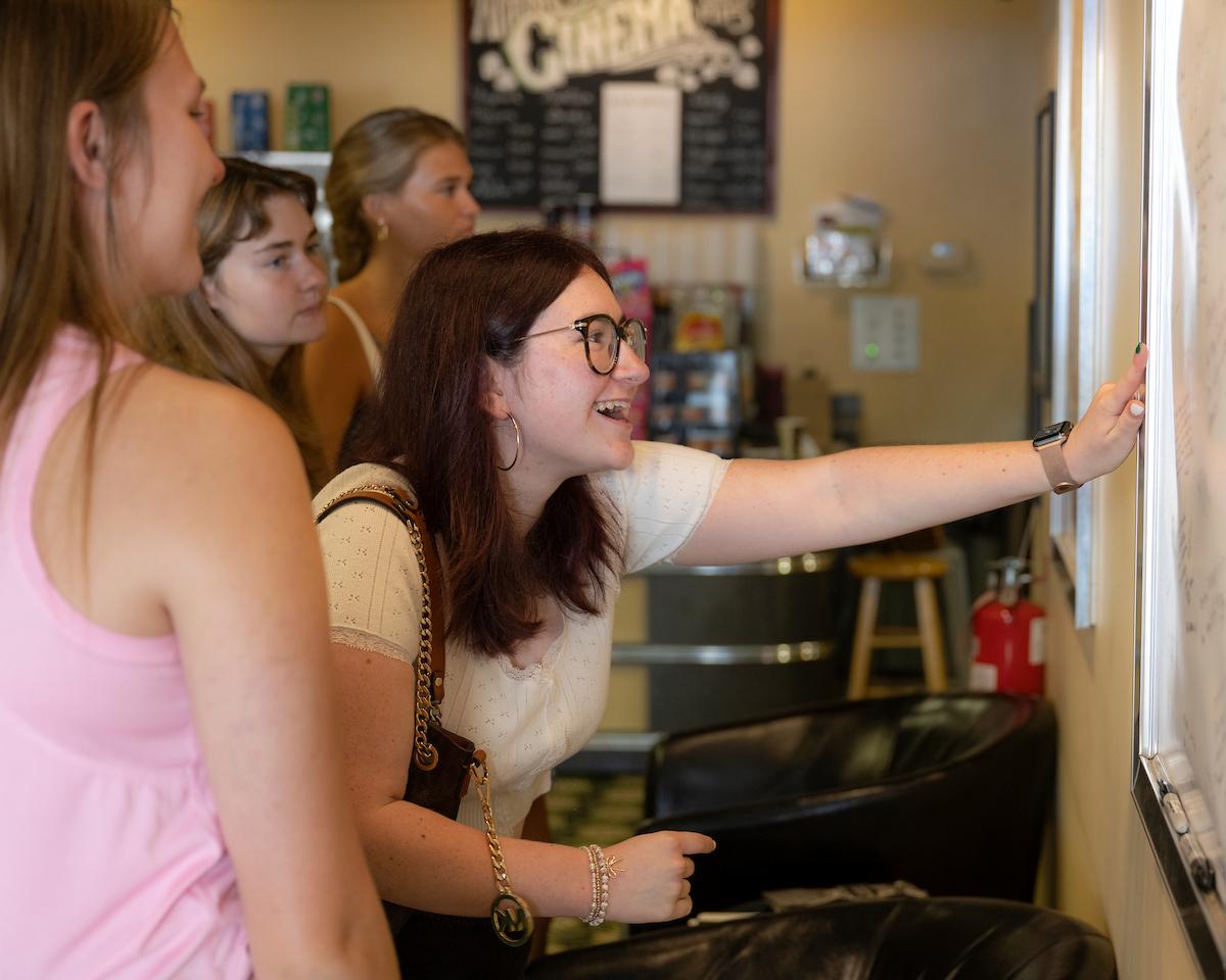 A student points at a white board in the Athena Cinema during the Early Experience Program