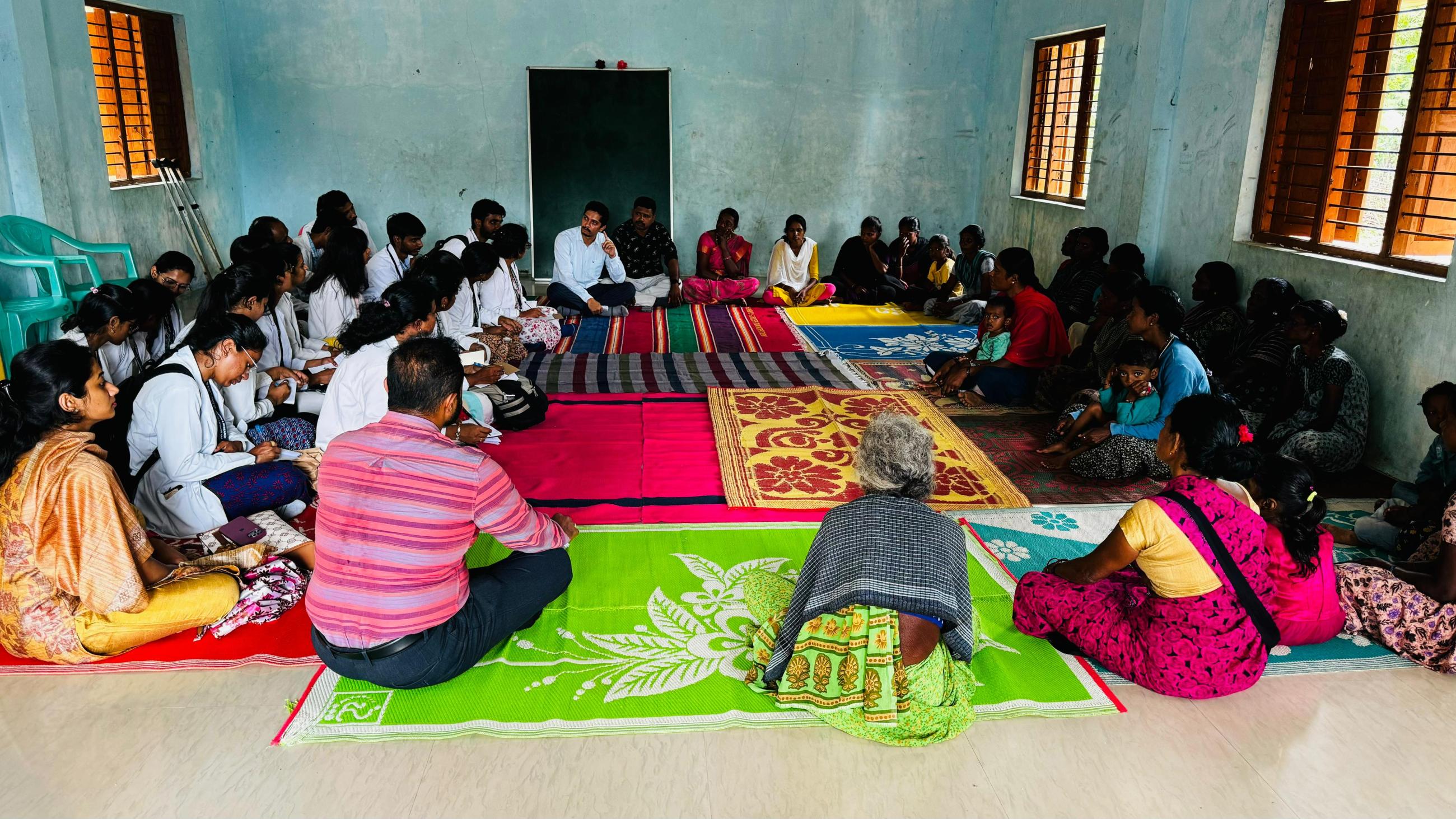 A circle of people sitting on colorful rugs