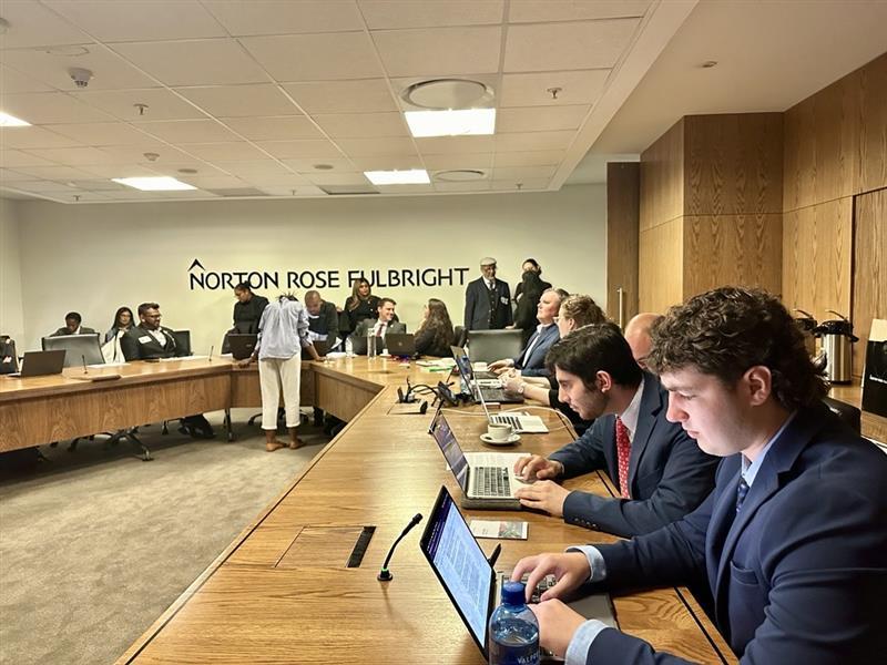 A group of people looking at laptops during a moot court experience. 