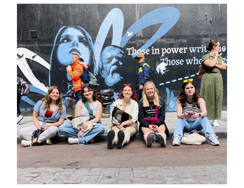 a group of 5 students sit in front of a graffiti wall in Ireland