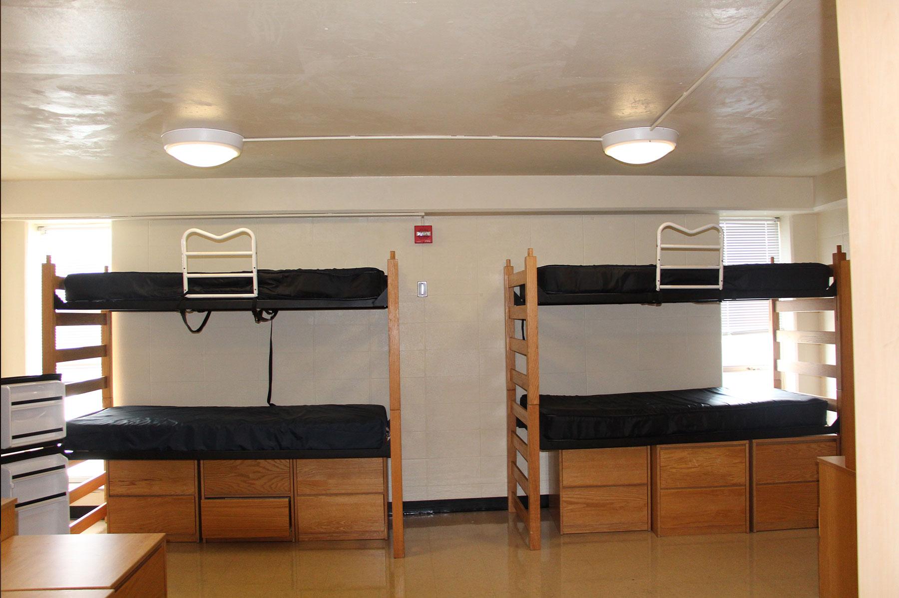 Inside a residence hall room in OHIO's Convocation Center, showing four bunked beds and 6 small storage dressers