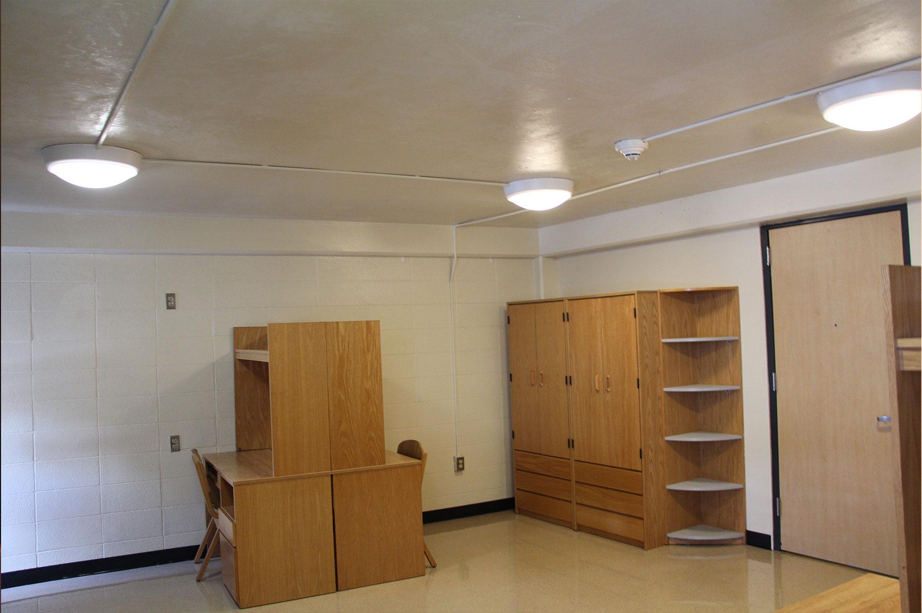 Inside a residence hall room in OHIO's Convocation Center, showing desks and built-in storage cabinets