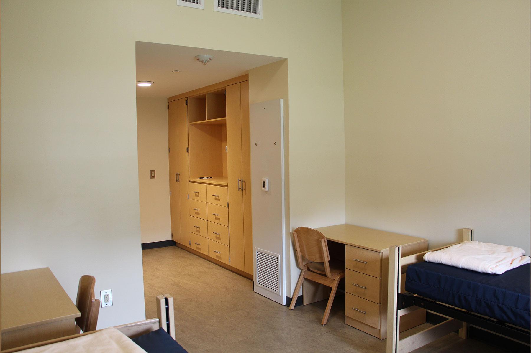 Example of a double suite dorm room on South Green, featuring a bedroom with 2 beds and desks, leading to another storage room