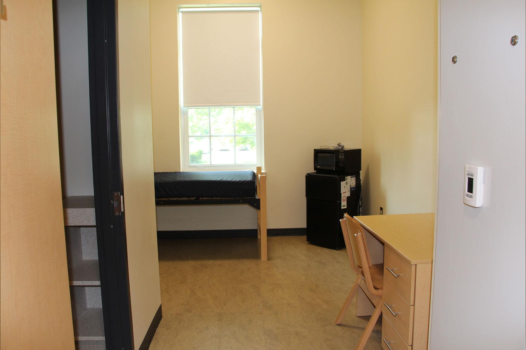 Example of a suite style dorm room on South Green, featuring a desk, built-in closet and bed