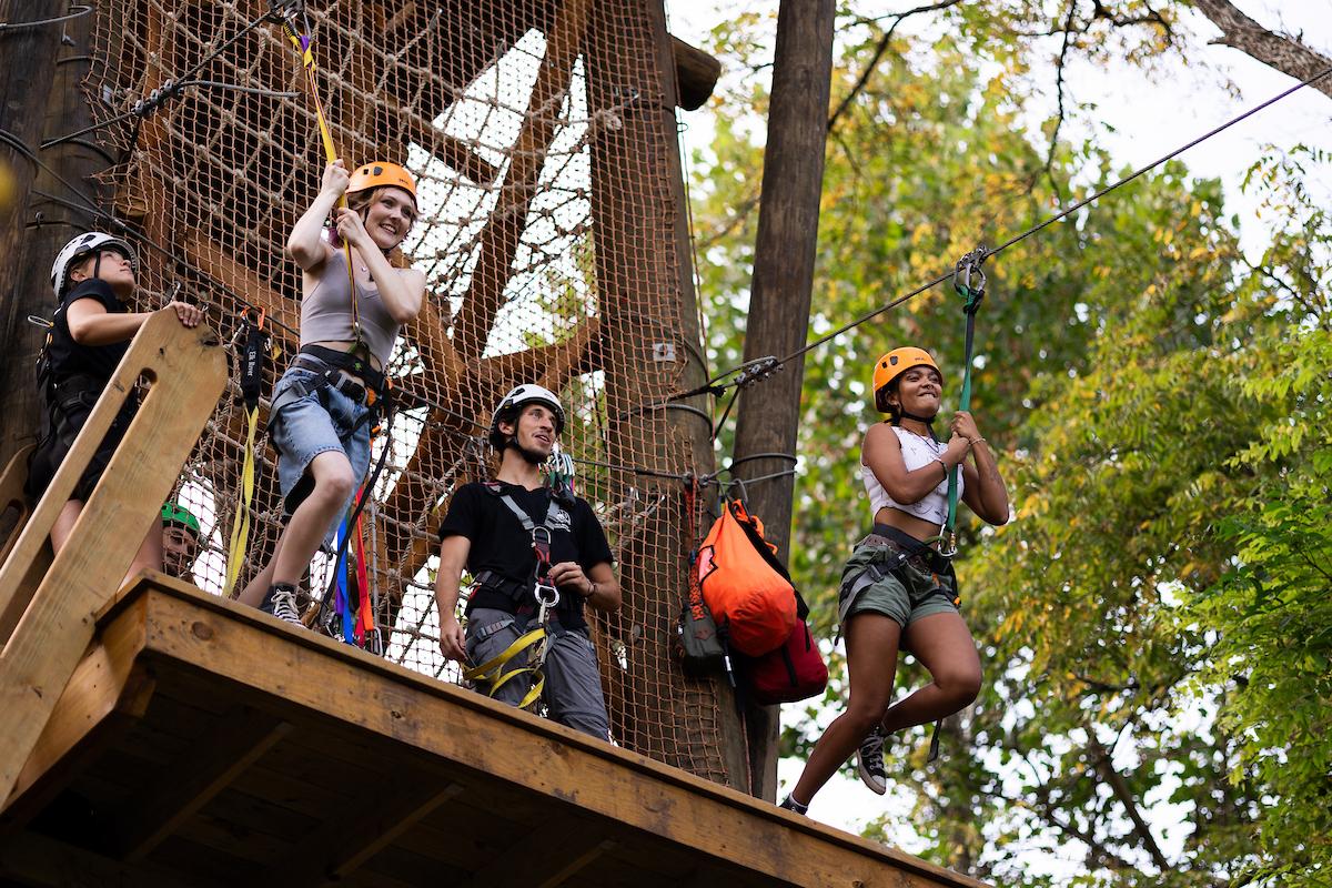 Two people jumping off of a zipline