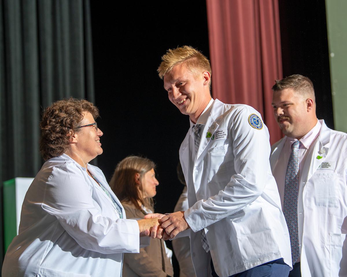 Medical students shake hands during a whitecoat ceremony
