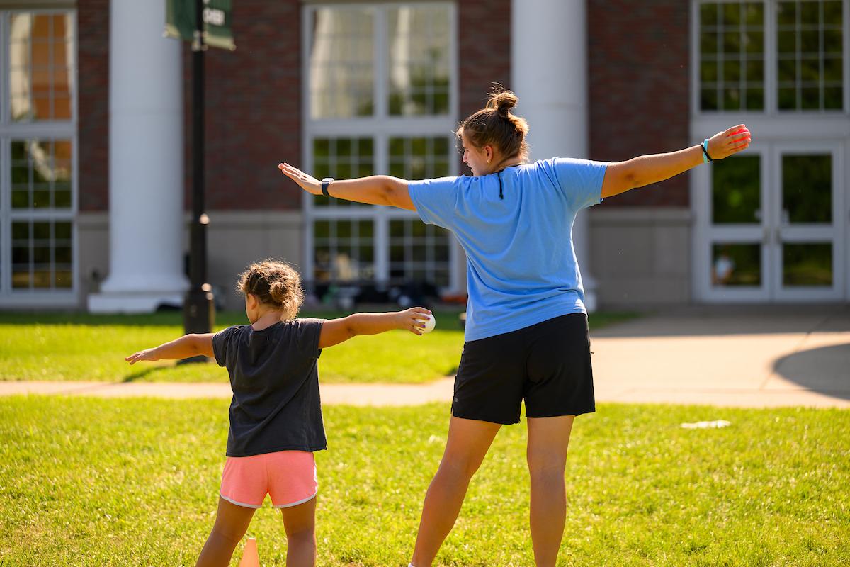Camp counselor does an exercise with a student during a summer camp